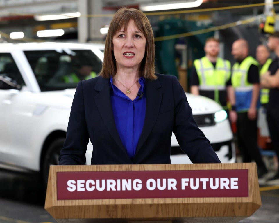 British Chancellor of the Exchequer Rachel Reeves delivers a speech at a podium with "SECURING OUR FUTURE" written on it, inside a Jaguar Land Rover factory.