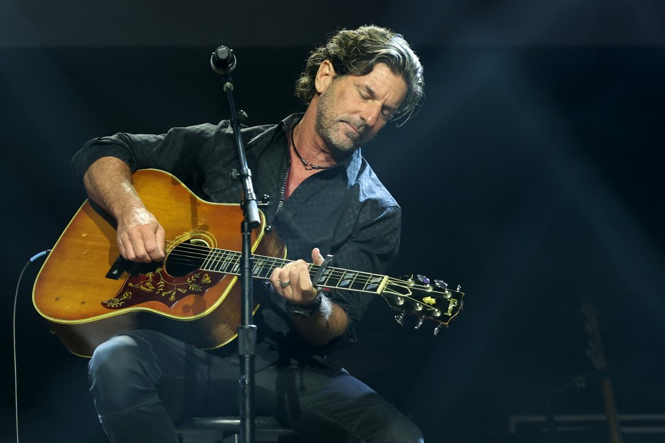 Songwriter Brett James performs on stage with an acoustic guitar.