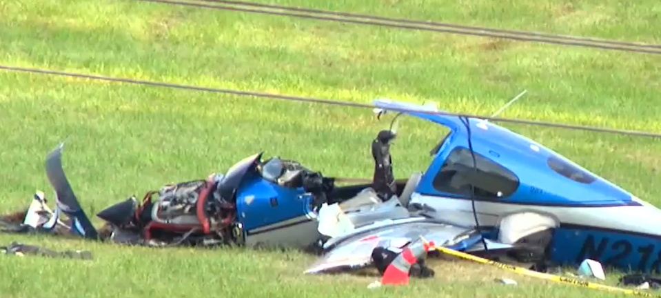 Wreckage of a small blue and white airplane in a grassy field.