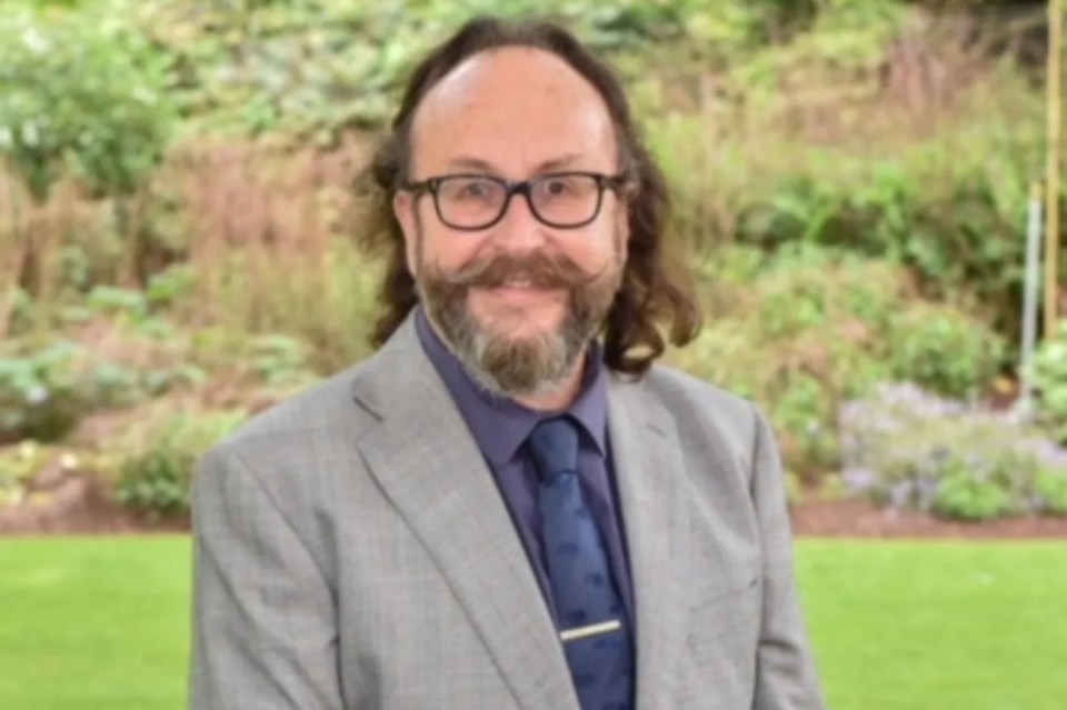 Dave Myers smiling in a light gray suit, purple shirt, and blue tie.