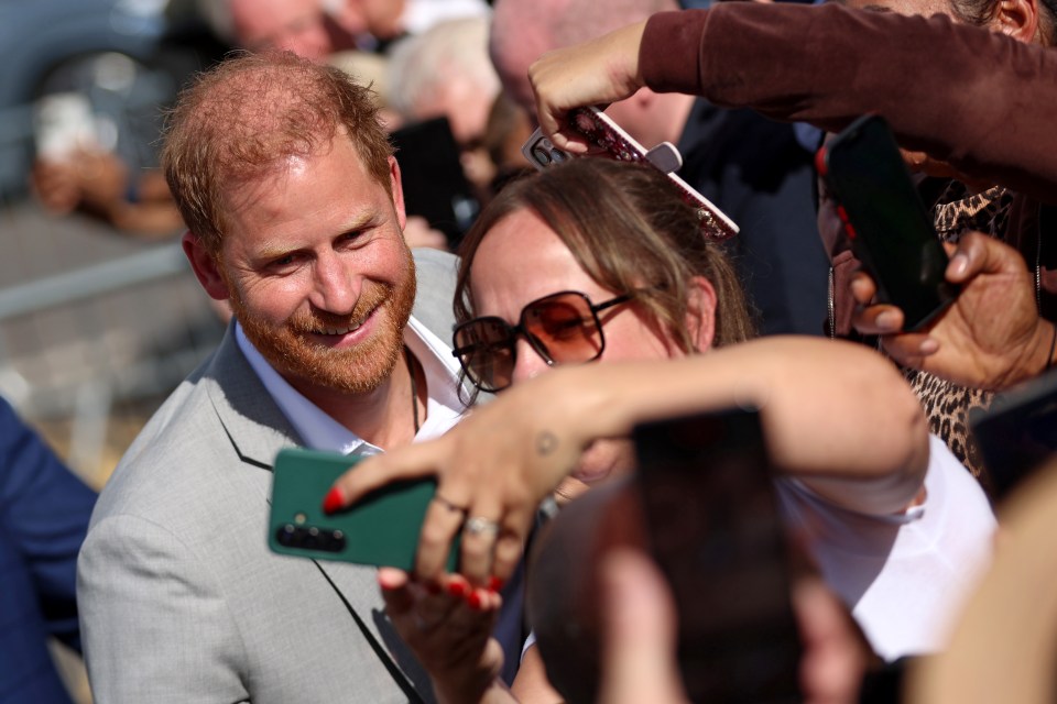 Prince Harry taking a selfie with fans.