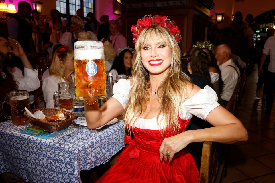 Heidi Klum onstage during the "Heidifest By Heidi Klum" at Hofbräuhaus Munich, holding a beer stein and wearing a red dirndl.
