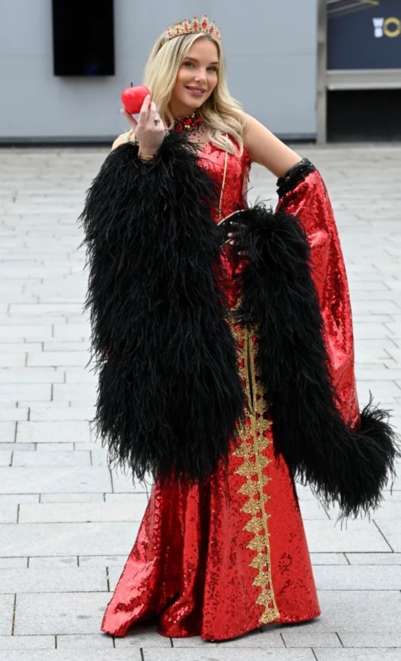 Woman in a red sequined gown and black feather boa holding a red apple.