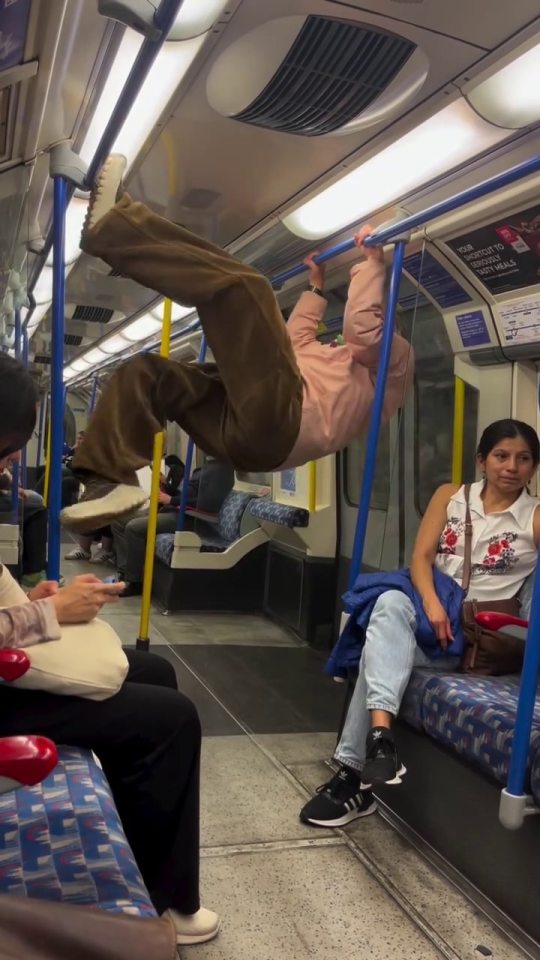 A man hanging from a handrail on a London Underground train.