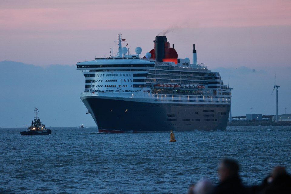 The Queen Mary 2 cruise liner docking in Liverpool, accompanied by a tugboat.