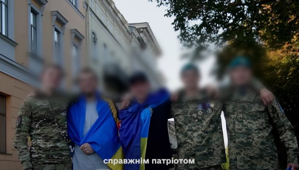 Blurred photo of Ukrainian soldiers and civilians with Ukrainian flags.