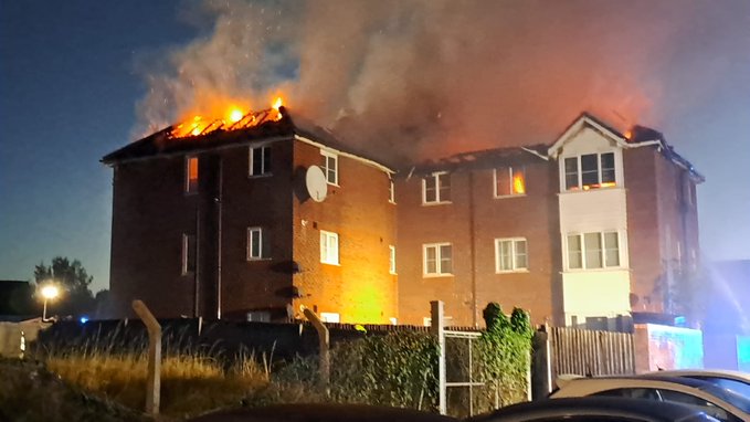 An apartment building on fire at night.