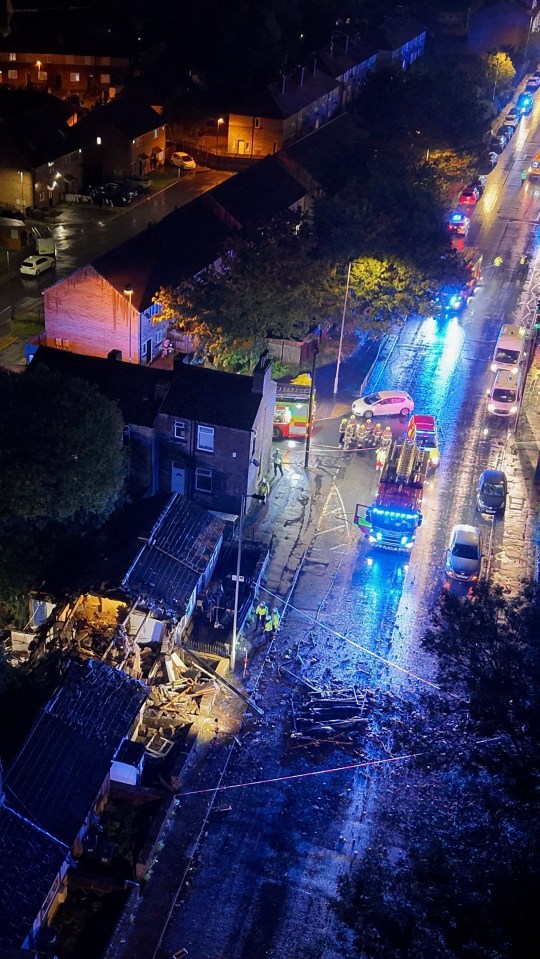 Aerial view of a residential explosion scene in Bradford, with emergency responders present.
