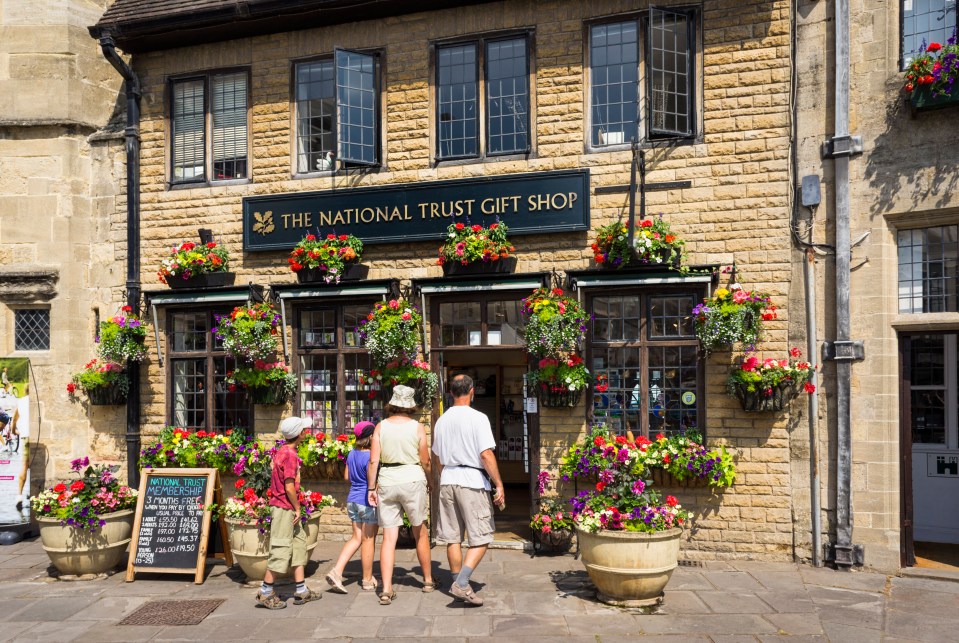 Family of tourists entering a National Trust gift shop in Wells, Somerset.