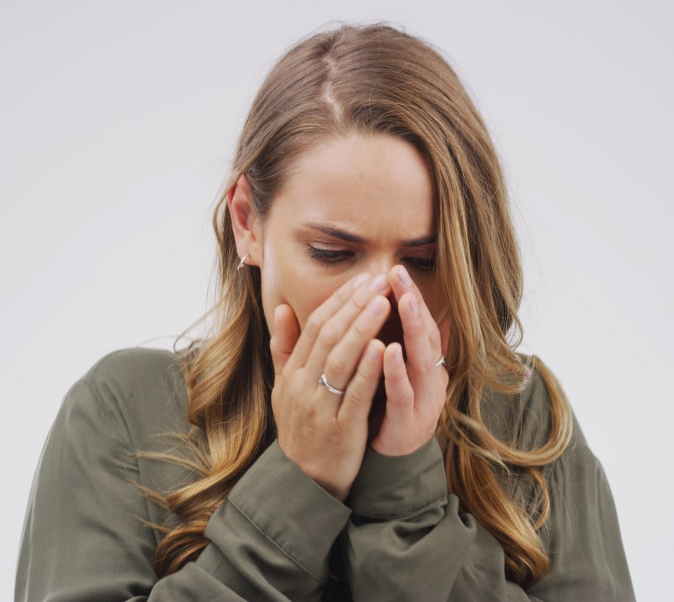 Woman covering her mouth and nose, appearing sick.