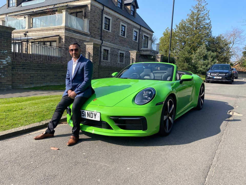 Man sitting on a green Porsche in front of his house.