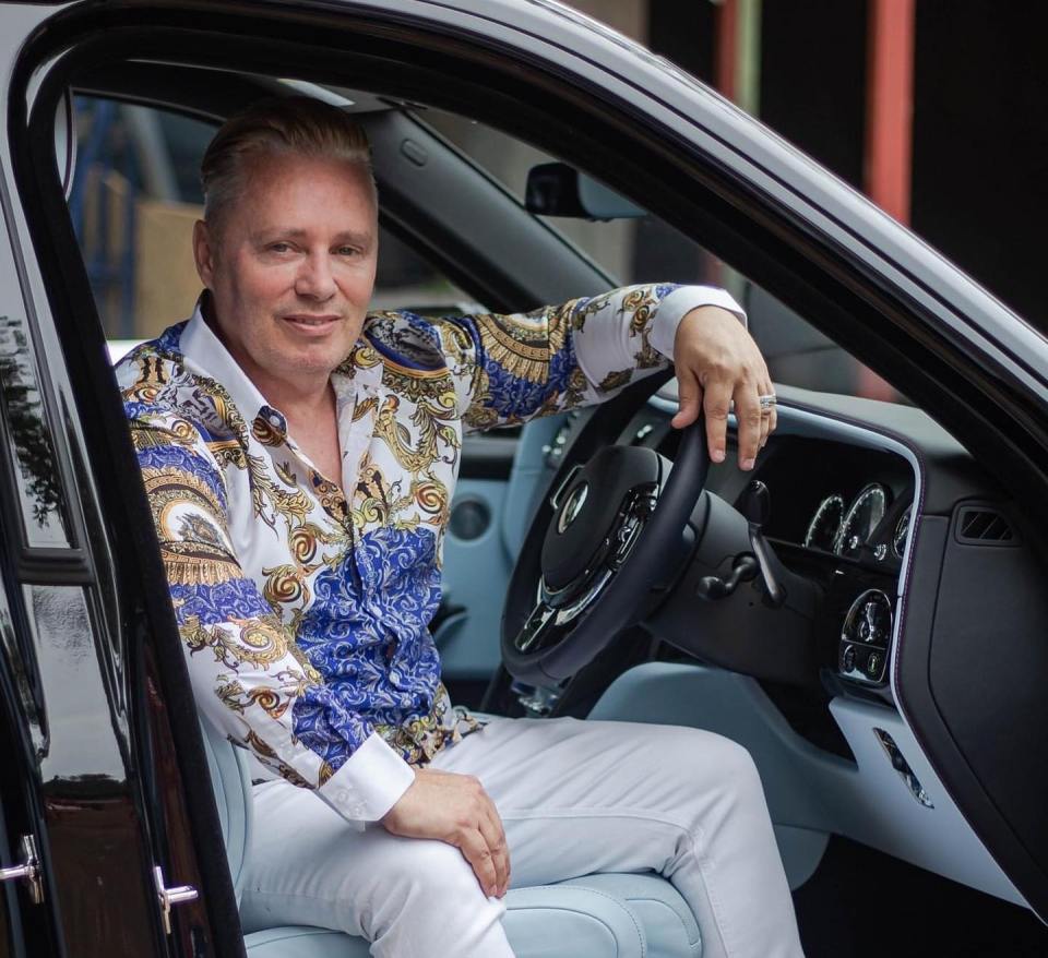 a man in a blue and white shirt is sitting in a car