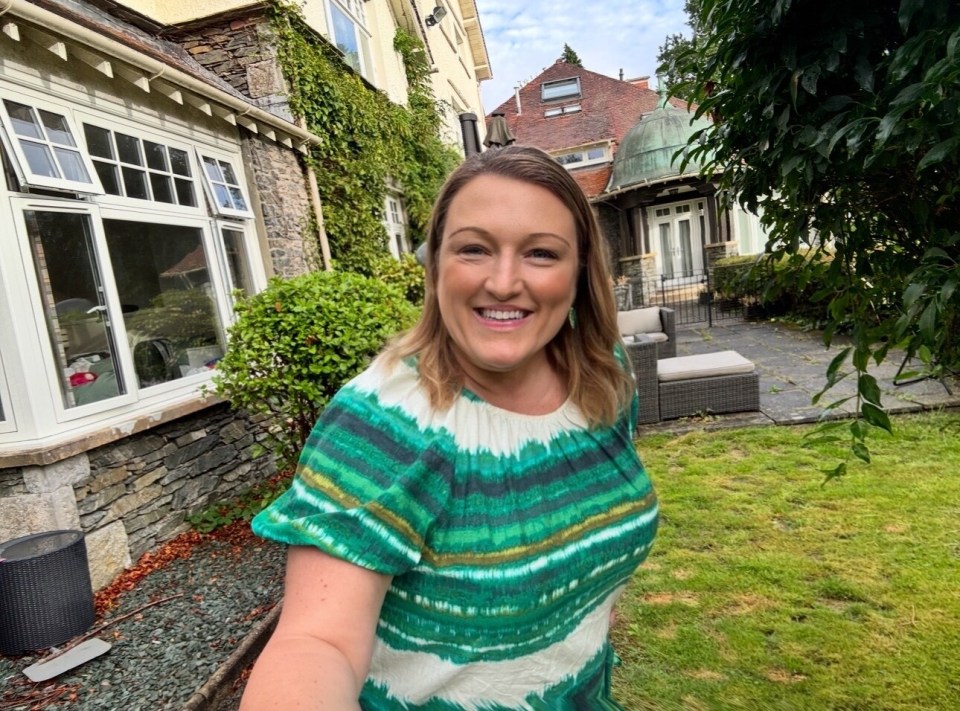 Woman in green dress smiling in a garden.