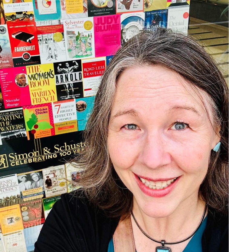 Close-up of a smiling woman in front of a wall of Simon & Schuster book covers.