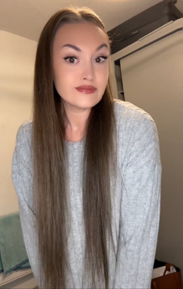 Woman with long brown hair in a grey sweater.