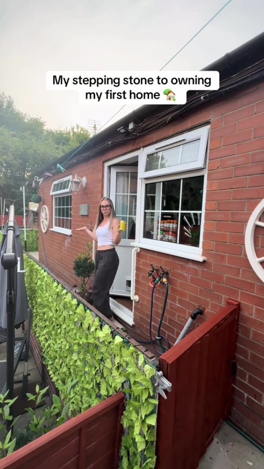 Woman standing outside her small house.