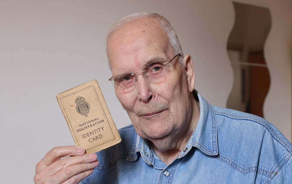 Elderly man holding up his World War II identity card.