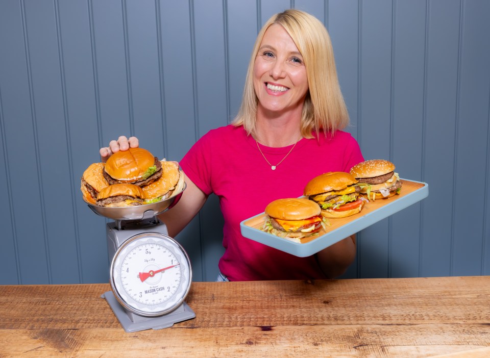 Woman holding several burgers on a scale and a tray.