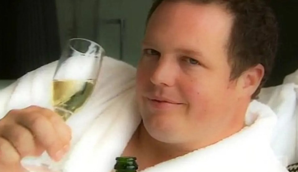 Man in bathrobe raising a glass of champagne.
