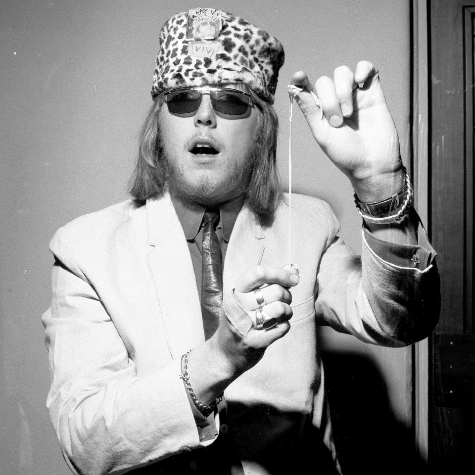 Black and white photo of Viv Prince, drummer for The Pretty Things, wearing a leopard print hat and sunglasses.