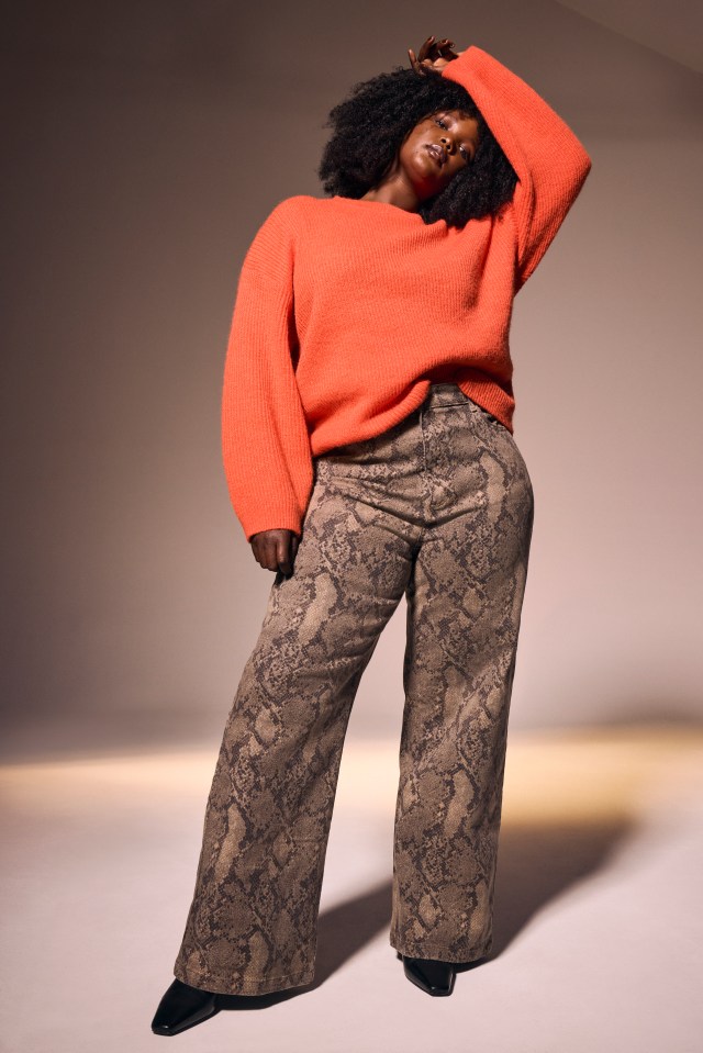 Model wearing an orange sweater and snakeskin pants.