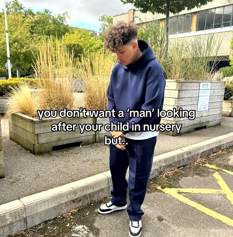 Man in navy hoodie and sweatpants standing outdoors, text overlay reads: "you don't want a 'man' looking after your child in nursery but.."
