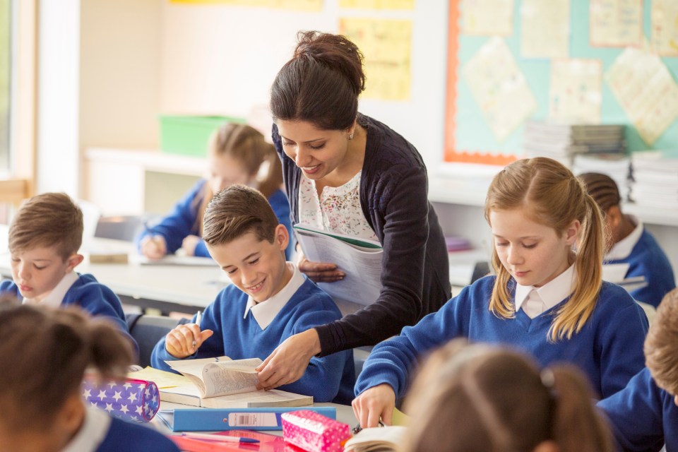 Teacher assisting elementary school students in a classroom.