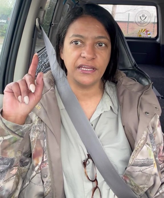 A woman in a car points her finger up.