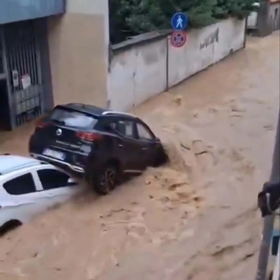 Two cars stuck in brown floodwaters in Meda, Italy, due to the overflowing Taro River.