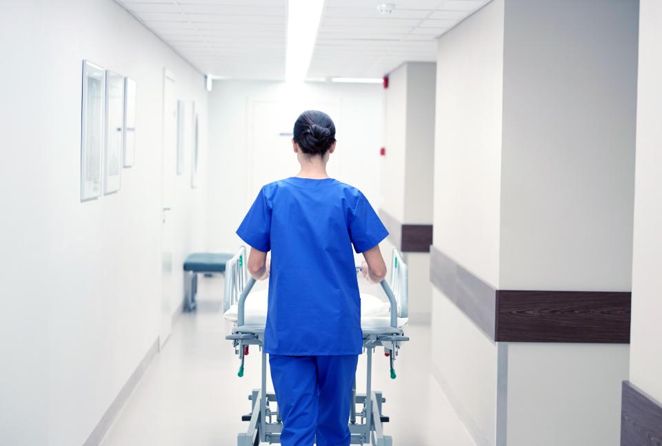 Nurse pushing a hospital gurney down a hallway.