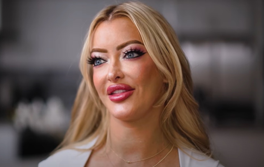 Linzee Ryder, a blonde woman with full lips and dramatic eye makeup, looks to her left.