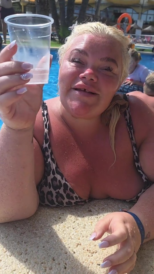 A woman holding a plastic cup in a swimming pool.
