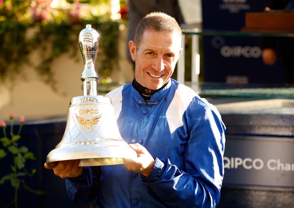 Jockey Jim Crowley holding the Qipco Champion Stakes trophy.