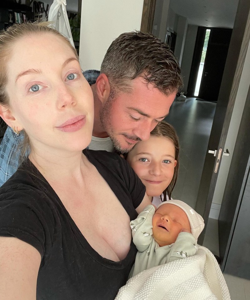 Family photo of a mother, father, daughter, and newborn baby.