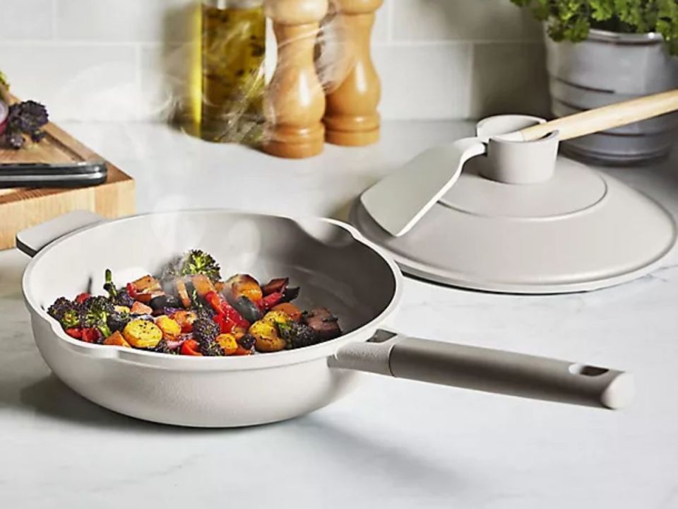 Sautéed vegetables in a light grey pan with lid and spatula.