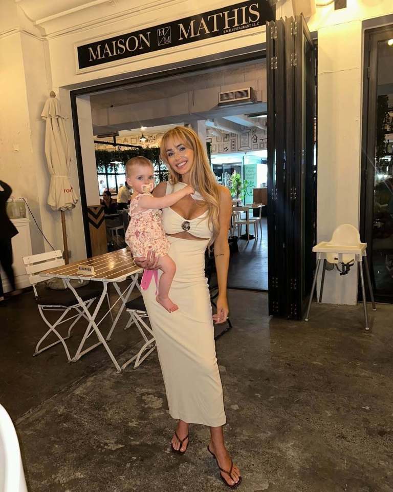 Woman holding baby outside restaurant.