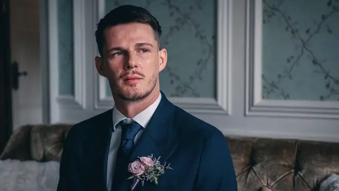 Steven from Married at First Sight wearing a dark blue suit with a pink rose boutonnière.