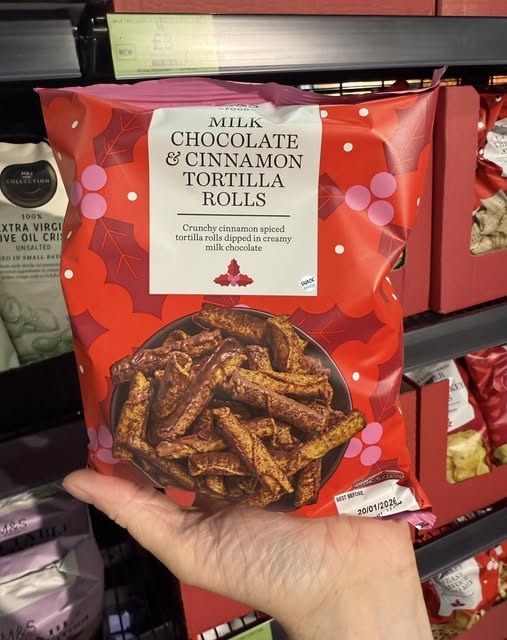 Hand holding a bag of milk chocolate and cinnamon tortilla rolls.