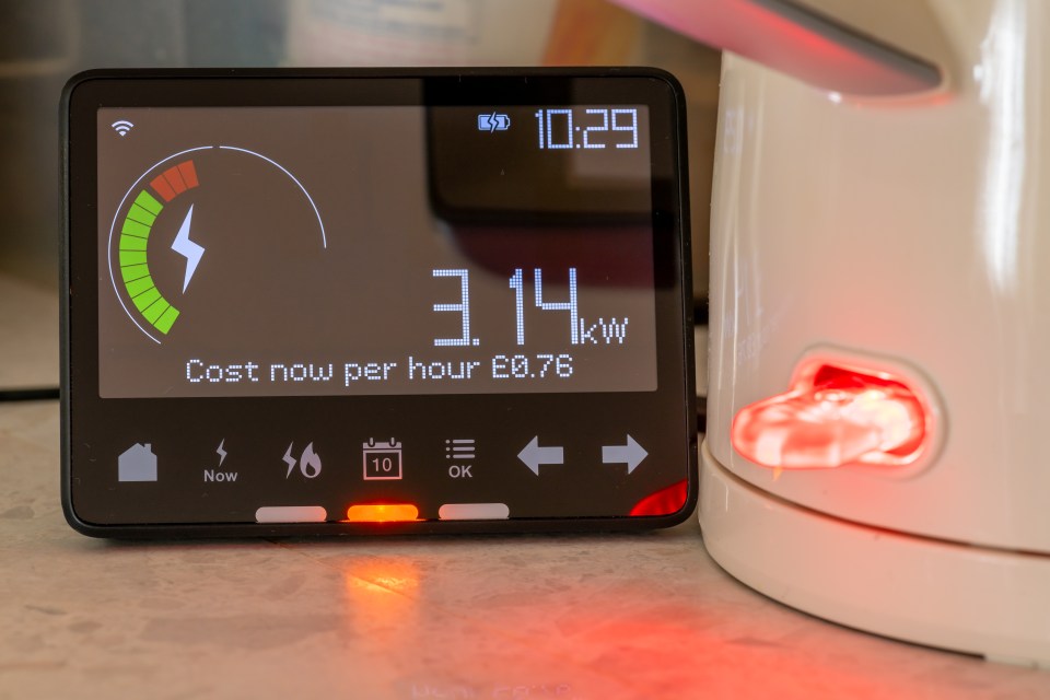 Smart meter displaying energy usage and cost next to a kettle.