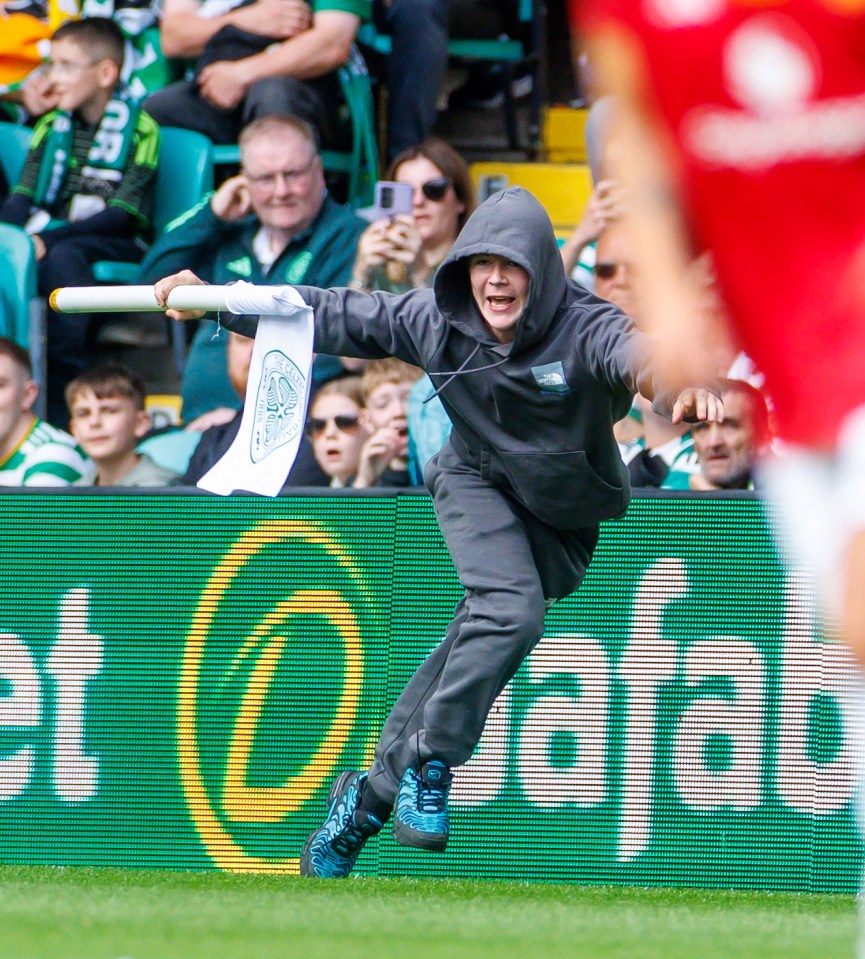 A pitch invader running with a corner flag.