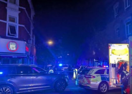 Police and an ambulance at a crime scene at night.