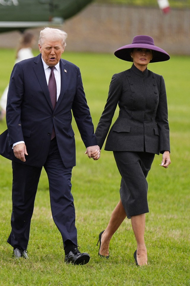 Donald and Melania Trump walking hand-in-hand in a grassy field.