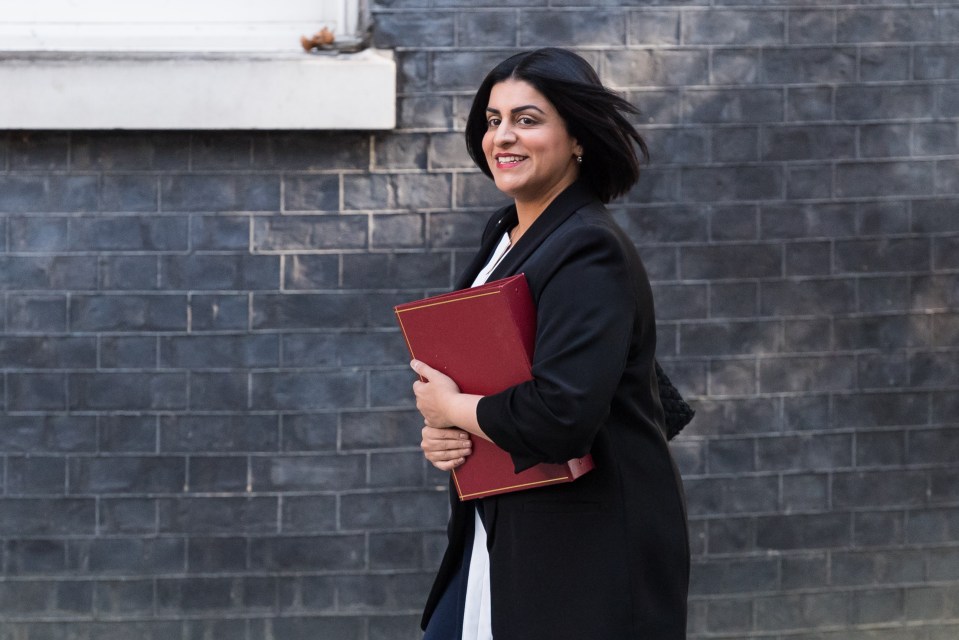 Shabana Mahmood, Secretary of State for the Home Department, smiles while carrying a red folder.