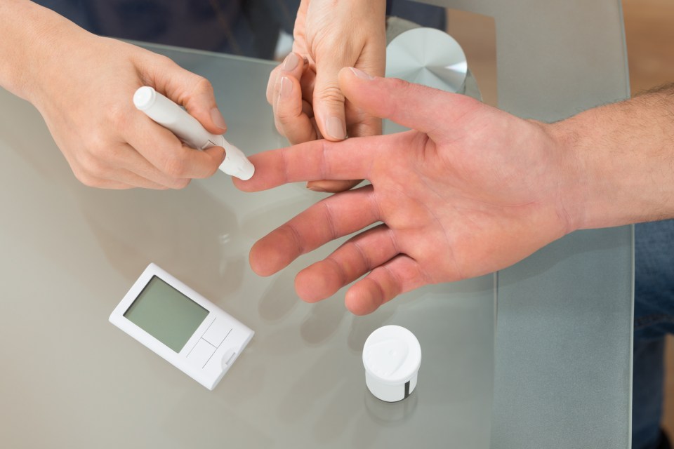 A doctor uses a lancelet on a man's finger for a blood sugar test.