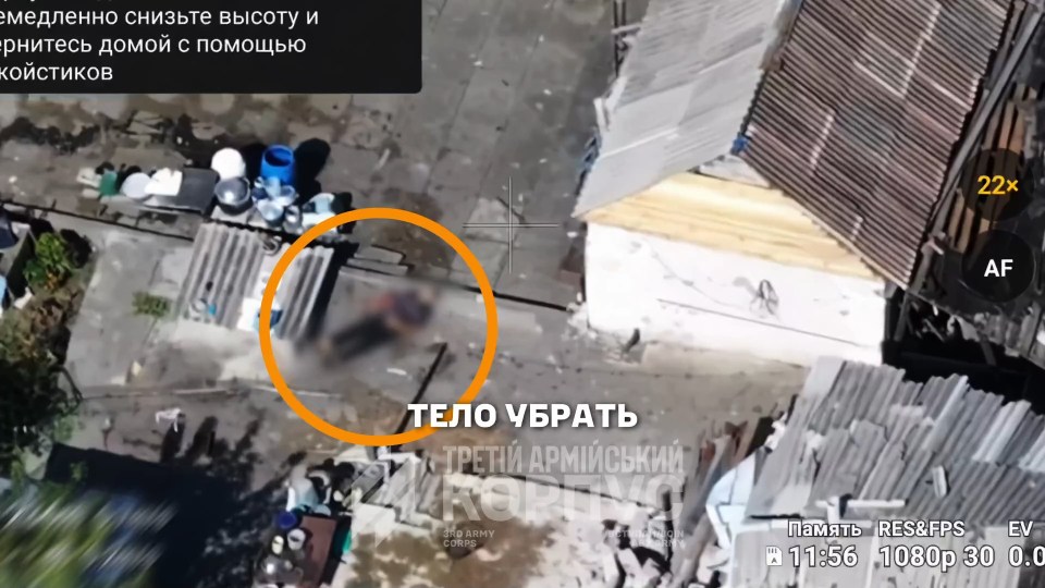 Aerial footage shows a blurred human body lying on the ground next to a small building, with an orange circle highlighting it, and text in Russian overlaying the image.