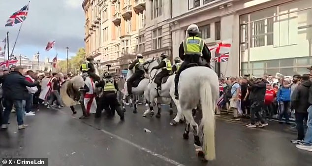 Police officers on horses and on foot rush in to rescue a man during the 'Unite the Kingdom' rally