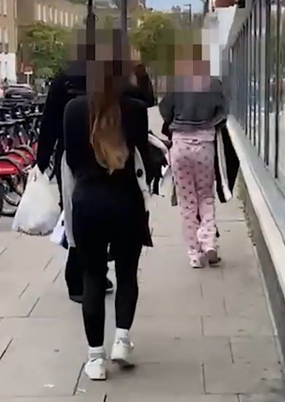 Three shoplifters carrying stolen clothes walk away from a H&M store.