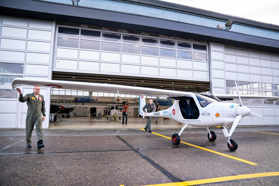 A Danish Air Force pilot standing by a white Pipistrel Velis Electro aircraft.