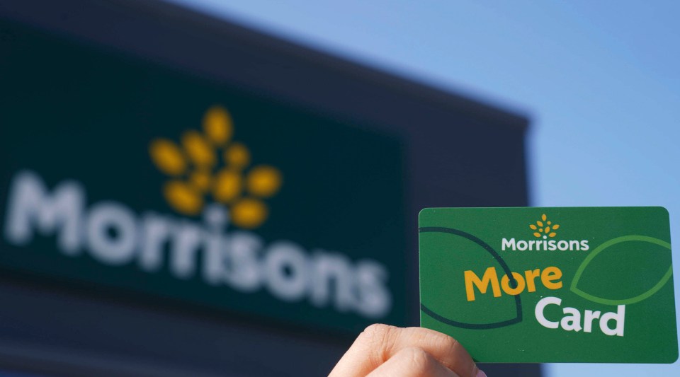 Morrisons More Card held in front of a blurred Morrisons store sign.