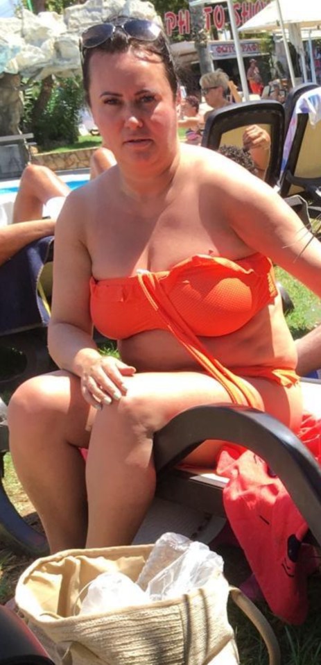 Woman in orange bikini top sitting by a pool.